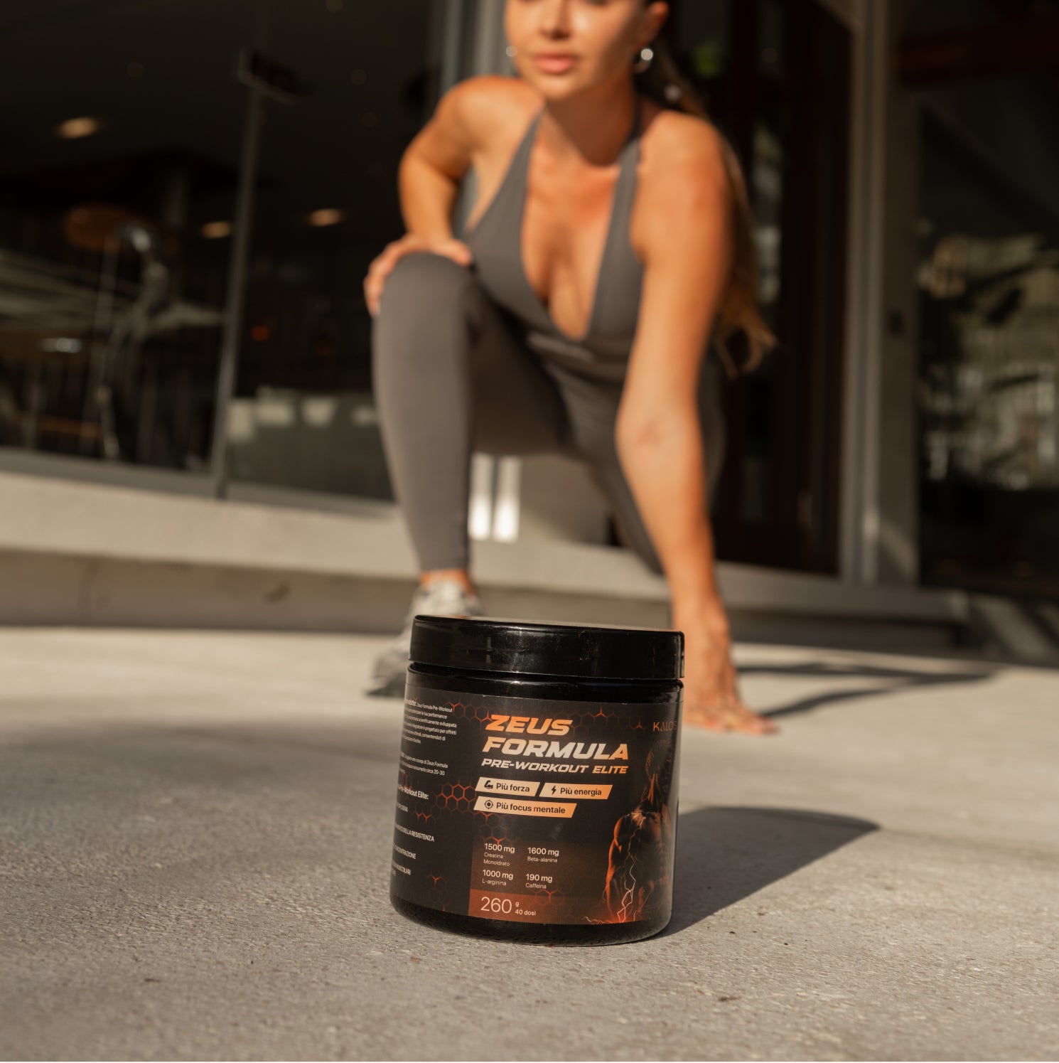 Zeus Formula Pre-Workout Elite, integratore per palestra e fitness che aumenta forza, energia e focus mentale. Contiene creatina, beta-alanina, L-arginina e caffeina. Donna si prepara all'allenamento.
